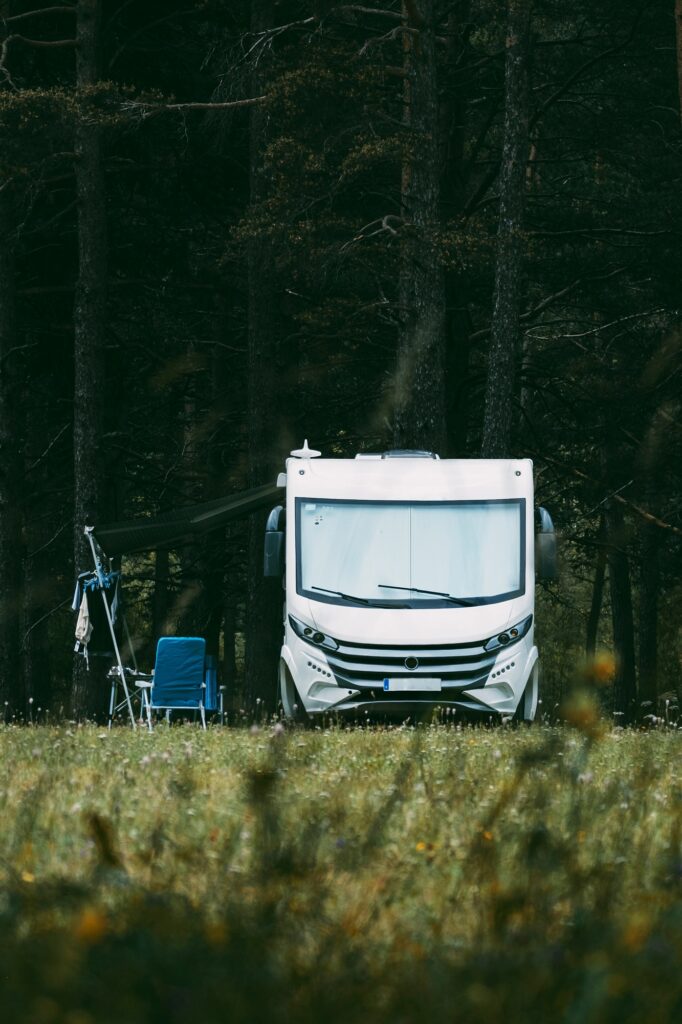Camper motorhome parked in the middle of the nature with woods forest in background - concept of fre