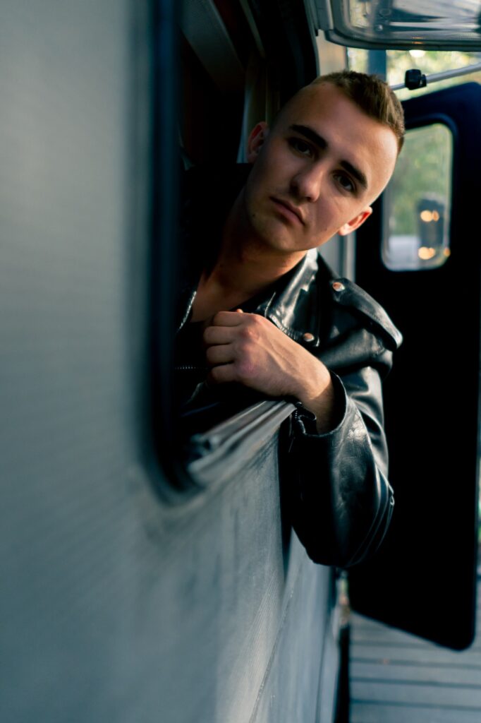 man in a leather jacket is driving trailer on a trip and looks thoughtfully out the open window