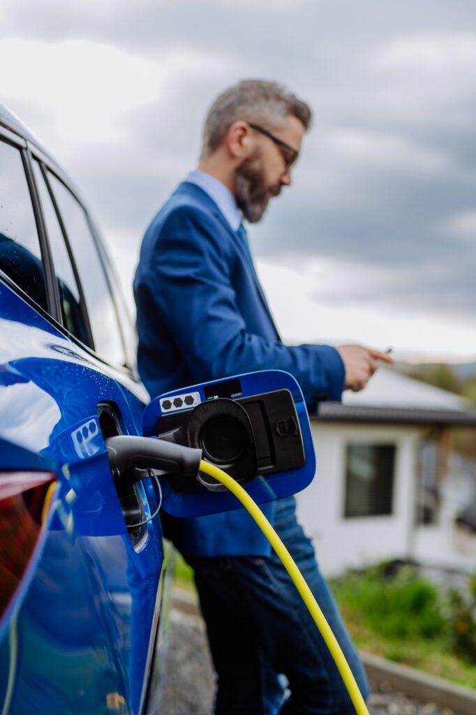 Mature businessman waiting for charging his electric car.