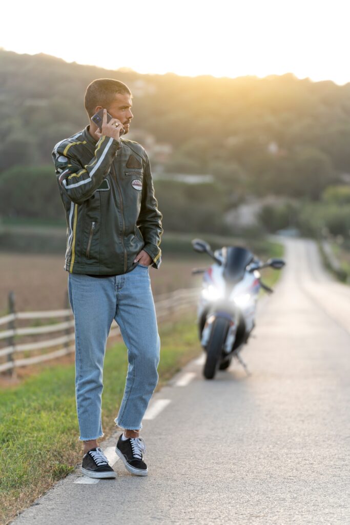 Young man with motorcycle breakdown on the road talking on the phone
