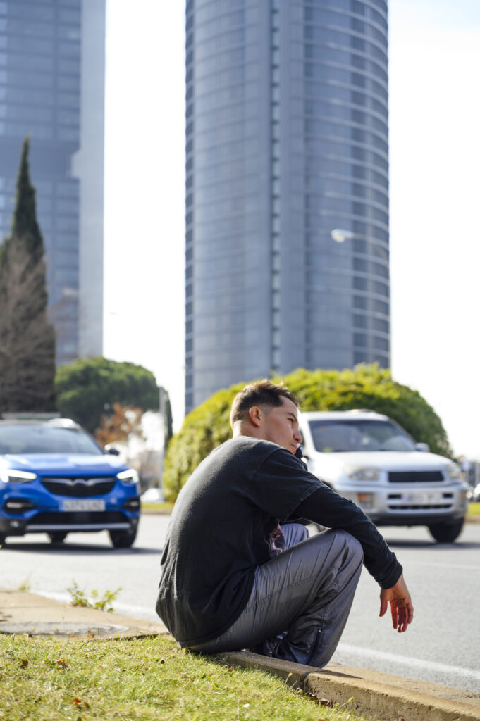 Kaukasischer Mann sitzt am Rand des Bürgersteigs der Stadt und wartet
