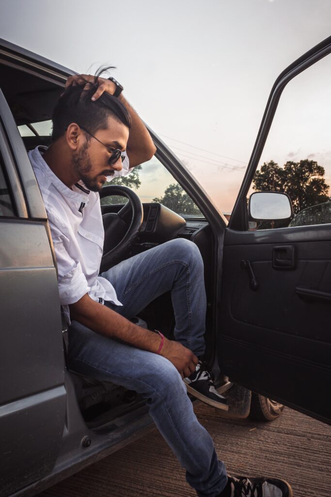 indischer Mann sitzt mit den Händen auf dem Kopf in einem Auto
